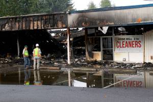 Kirkland firefighters and Puget Sound Energy staff examine the aftermath of a four-hour fire that destroyed the Rose Hill Village and annihilated Decks and Spas. Kailan Manandic/staff photo