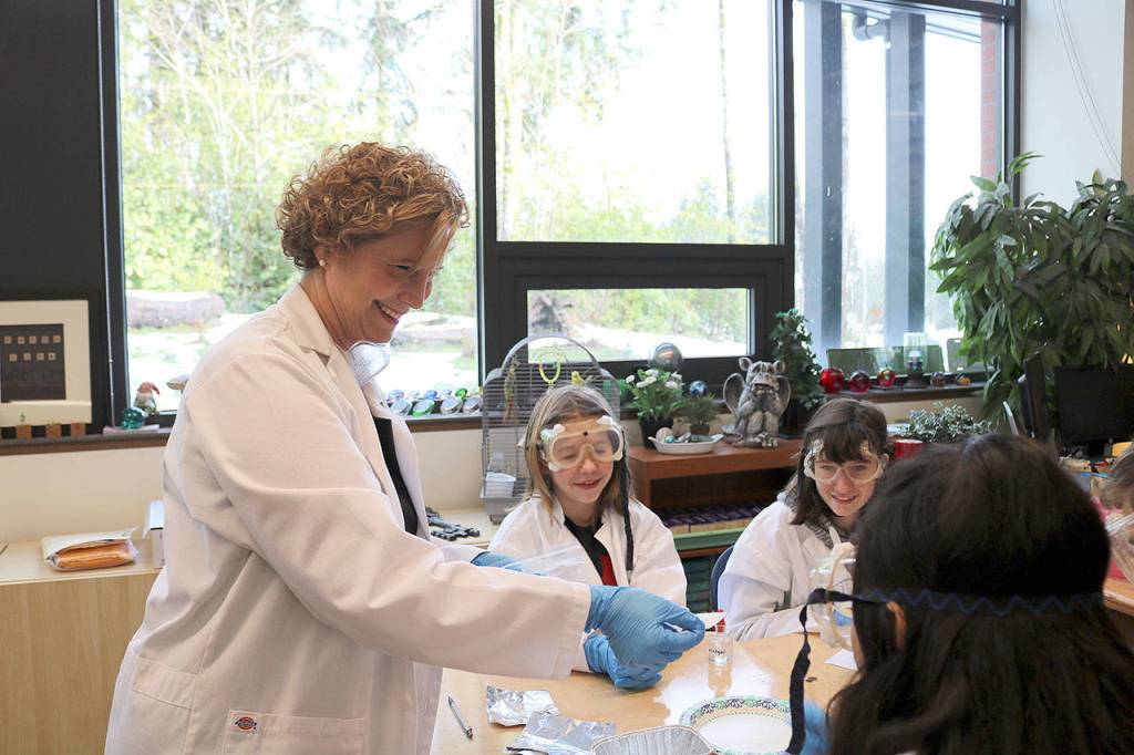 Stephanie Quiroz/staff photo                                 Brigitte Tennis helped students with their science experiments to help identify which idiom best fit the chemical reaction they produced on Feb. 20.
