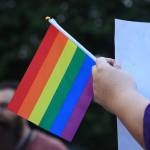 A supporter of the Drag Queen Story Hour event holds a sign and Pride flag standing across the parking lot of the Fairwood Library from a protester on June 27. Aaron Kunkler/staff photo