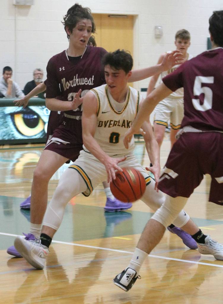 Owl junior Roman Peterson, middle, drives past a pair of Northwest players. Andy Nystrom/ staff photo