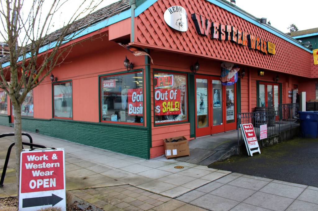 Open signs and sale signs mark the windows of Redmond Work and Western Wear in Redmond on March 4. Mitchell Atencio/staff photo