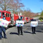 L-R: AMR Supervisor Kevin Devine, SKFR Fire Chief Vic Pennington, Federal Way Police Chief Andy Hwang and King County Medic One Chief Andy Tait hold signs made by Federal Way residents Justin and Darianne Westcott and their kids. Olivia Sullivan/staff photo