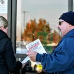 Kevin Flynn, right, a meat-cutter with the Marysville Albertsons, hands a leaflet to a shopper during an informational campaign on Wednesday, Nov. 9, 2022. Flynn was one of about a dozen grocery store workers handing out leaflets to shoppers about the proposed merger between Albertsons and Kroger. (Mike Henneke / The Herald)