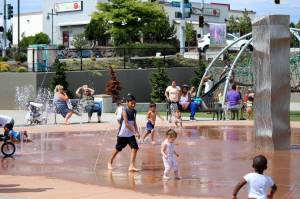 Families splash and play in the water at at Federal Ways Town Square Park to cool off from a previous heatwave in the region. (File photo)